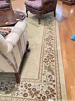Full view of rug beside furniture highlighting border and field