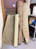 Four rolled area rugs leaning against wall