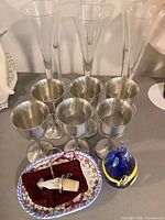 Group shot showing metal goblets, glass flutes, tray, stopper, blue glass piece
