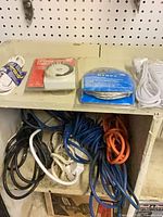 Shelf with packaged GE extension cord, mechanical timer, Dynex USB cable, coiled grey cord