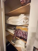 Shelf with multiple bedding items: mattress pad, pillowcases, quilt, throws