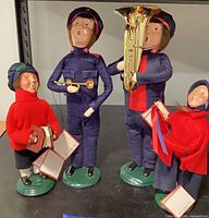 Four caroler figurines showing instruments and songbooks