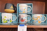 Front view of all five mugs on shelf, four boxed and one unboxed
