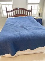 Full bed made with blue quilt over mattress
