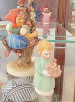 Girl on flowering apple tree branch and angel child figurines visible in display case