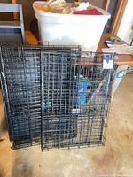Collapsed black wire dog crates leaning against wall