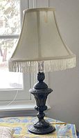 Table lamp with cream fringed shade on table
