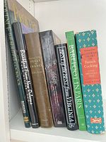Group shot of all eight cookbooks on shelf showing spines