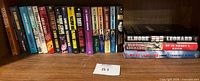 Full shelf view showing approximately 18 books in one row with lot tag 81