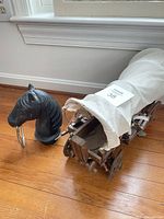 Horse head bookend next to wooden covered wagon model on hardwood floor