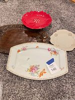 All four items grouped: porcelain platter, wooden tray, red bowl, cream dish
