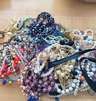 Pile of assorted necklaces showing varied beads, faux pearls, gold-tone chains, cameo pendant