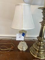 Small cut-glass and brass lamp with bell shade and cord visible