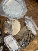 overall lot with two round platters, napkin rings in boxes, utensils in bag, metal tray, glass dish