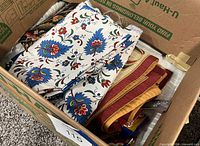 Box containing folded floral and solid pattern table linens