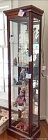 Full front view of tall mahogany curio cabinet showing glass door, shelves and contents