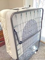 Bed folded upright showing metal frame, wire springs, attached mattress