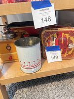 Overall shot showing cookie tin, flour sifter and coffee grinder on shelf