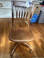 Front view of wooden swivel chair showing seat, backrest and casters