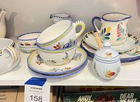 Group of hand-painted bowl, saucers, pitcher, sugar bowl on shelf