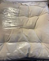 Front view of one packaged white tufted cushion