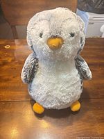 Front view of grey and white plush penguin with yellow beak and feet
