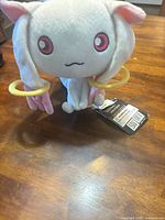 Front view of Kyubey plush showing facial features, ear rings, and tags