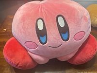 Front view of Kirby plush showing eyes, cheeks, mouth, feet