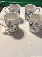 Four mugs on tray, showing pattern and some saucers