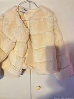 Front view of ivory faux fur jacket on hanger
