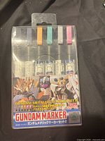 Front view of sealed Gundam Marker Metallic Set 2 showing six markers and color caps