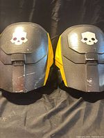 Front view of both pauldrons showing overall design, color scheme, skull emblems, and surface wear