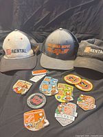 Group shot of three caps, key-chain light and patches