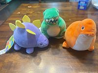 Front view of three overstuffed dinosaur plush toys