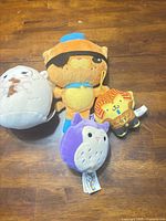 Group view of all four plush toys on wooden surface