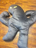 Front view of black Bruno cat pillow showing yellow eyes and overall shape