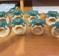 Eight intact frog napkin rings aligned on tabletop