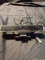 Front view of Xfinity webcam showing lens, microphone grilles, clip mount and USB cable