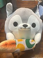 Front view of grey and white husky plush holding Subway sandwich