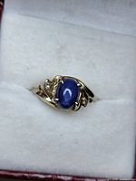 Close-up of ring showing sapphire cabochon, diamond accents and gold setting