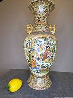 Full view of tall Satsuma style vase beside lemon for scale