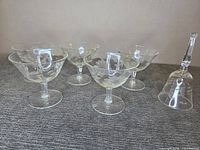 Five Cornflower etched sherbet glasses and one etched bell displayed on tabletop