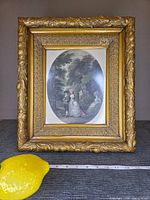 Front view of ornate gilt frame with engraving and scale items