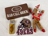 Group view of all four items: foam brick, plush bear, helmet hanger, packaged lure