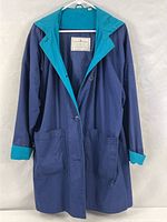 Full view of navy and teal hooded raincoat on hanger