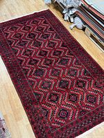 Full view of red Persian rug on wood floor