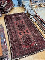 Full view of red Persian tribal rug on wood floor