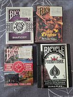 Front view of four Bicycle decks: Rhapsody, Age of Dragons, Canada Four Seasons, Prestige
