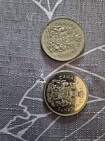 Reverse sides of both 50-cent coins showing Canadian coat of arms and dates 1974, 1985