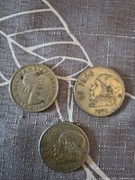 Obverse sides of three coins showing portraits and Un Peso inscription